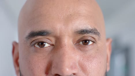 portrait of happy biracial male doctor looking at camera in corridor, slow motion