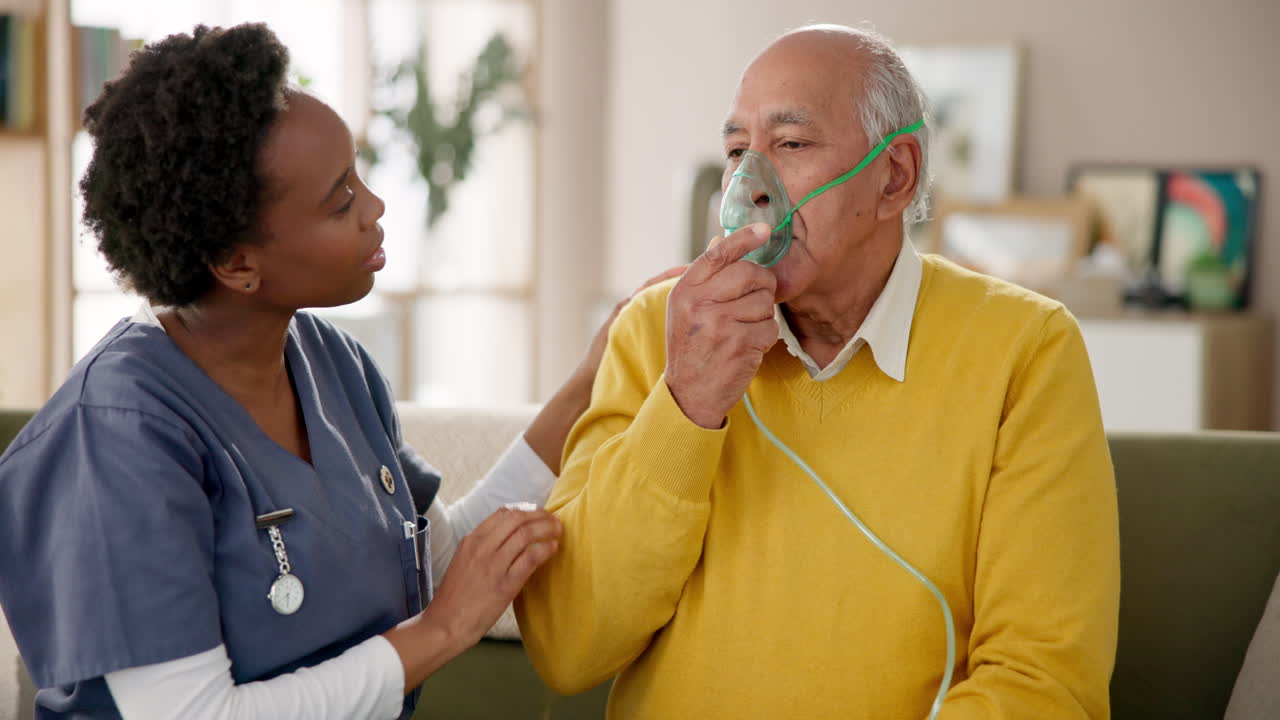 Nurse assisting elderly man with oxygen mask at home