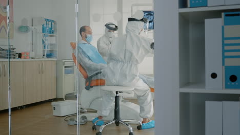 orthodontists and patient wearing ppe suits in oral cabinet