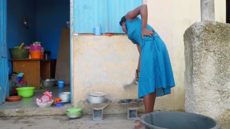 Black-african-woman-from-ghana-stoking-charcoal-stove-to-prepare-banku,-a-dough-ball-made-from-leavened-flour,-typical-of-Ghana