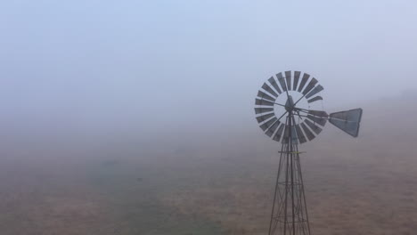 aerial flyby of abandoned antique windmill in thick fog