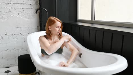 cheerful woman washing arm in bathtub