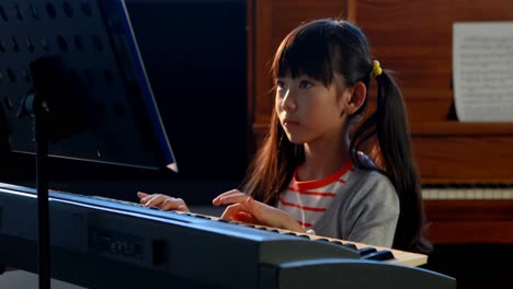 schoolgirl learning electric piano in music class 4k
