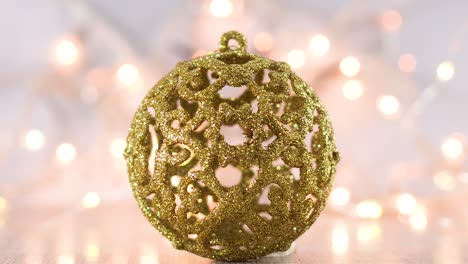 gold christmas ornament with blinking lights behind