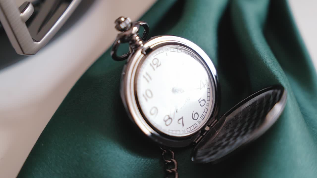 Reloj de bolsillo plateado clásico con cadena sobre tela verde