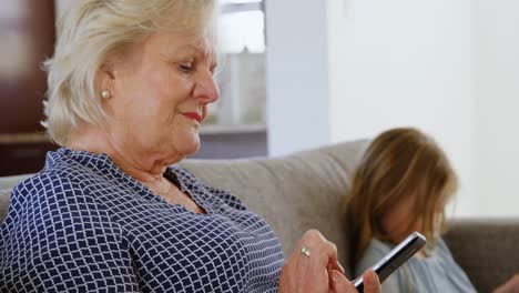 Grandmother-using-mobile-phone-in-living-room-4k