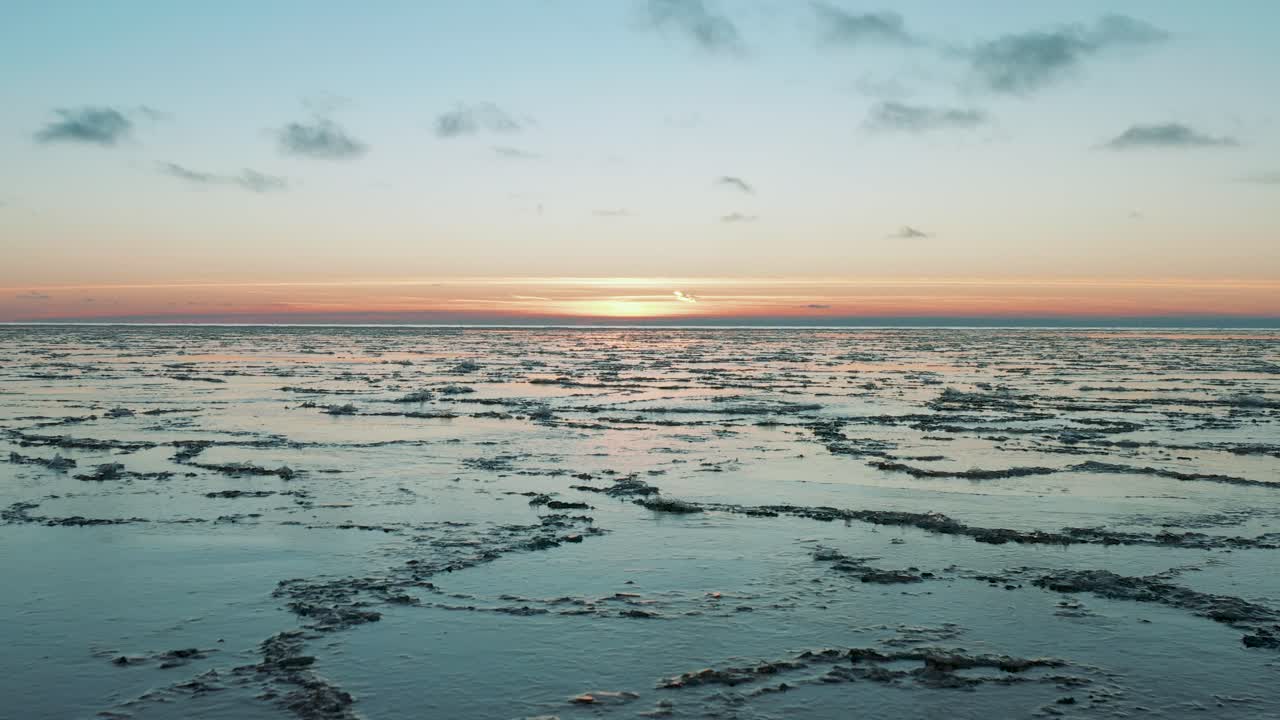 drone volando sobre el mar en calma con hielo derretido en la superficie al atardecer, amanecer