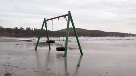 swings moving slowly in the wind on a flooded beach