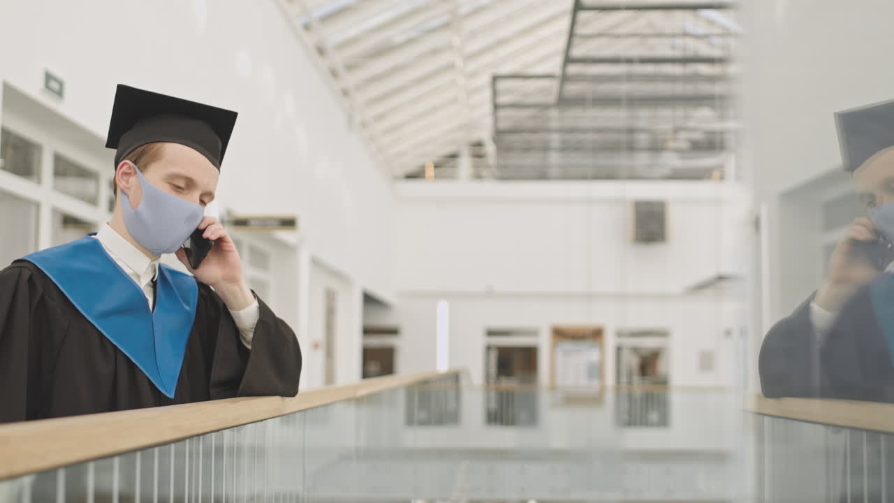 Cheerful Male Graduate Making Telephone Call in University