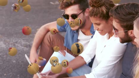 varios emojis de cara flotando contra un grupo de amigos que usan una tableta digital