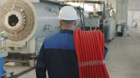 male plant worker in hard hat carrying hdpe pipes