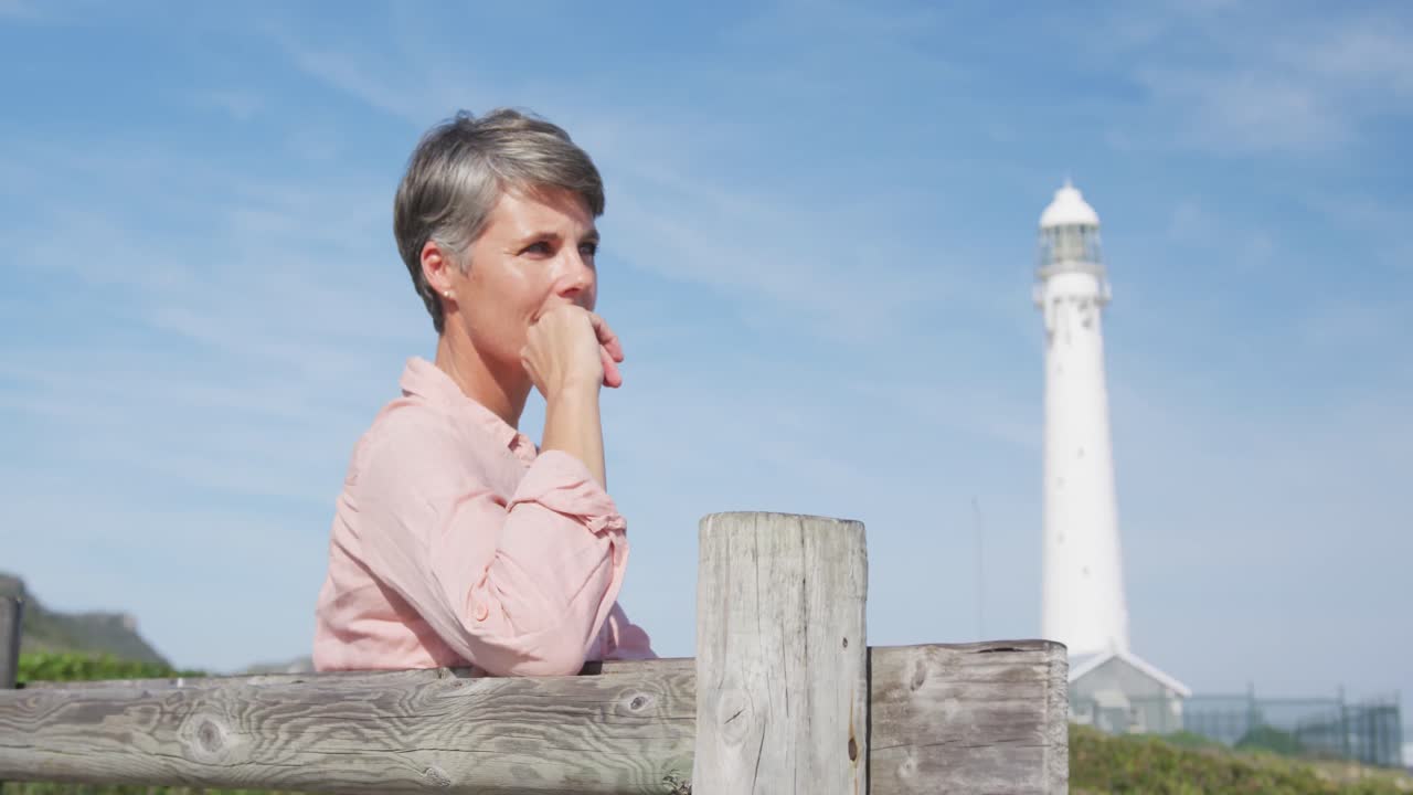 Caucasian woman enjoying free time by the sea on sunny day sitting on bench