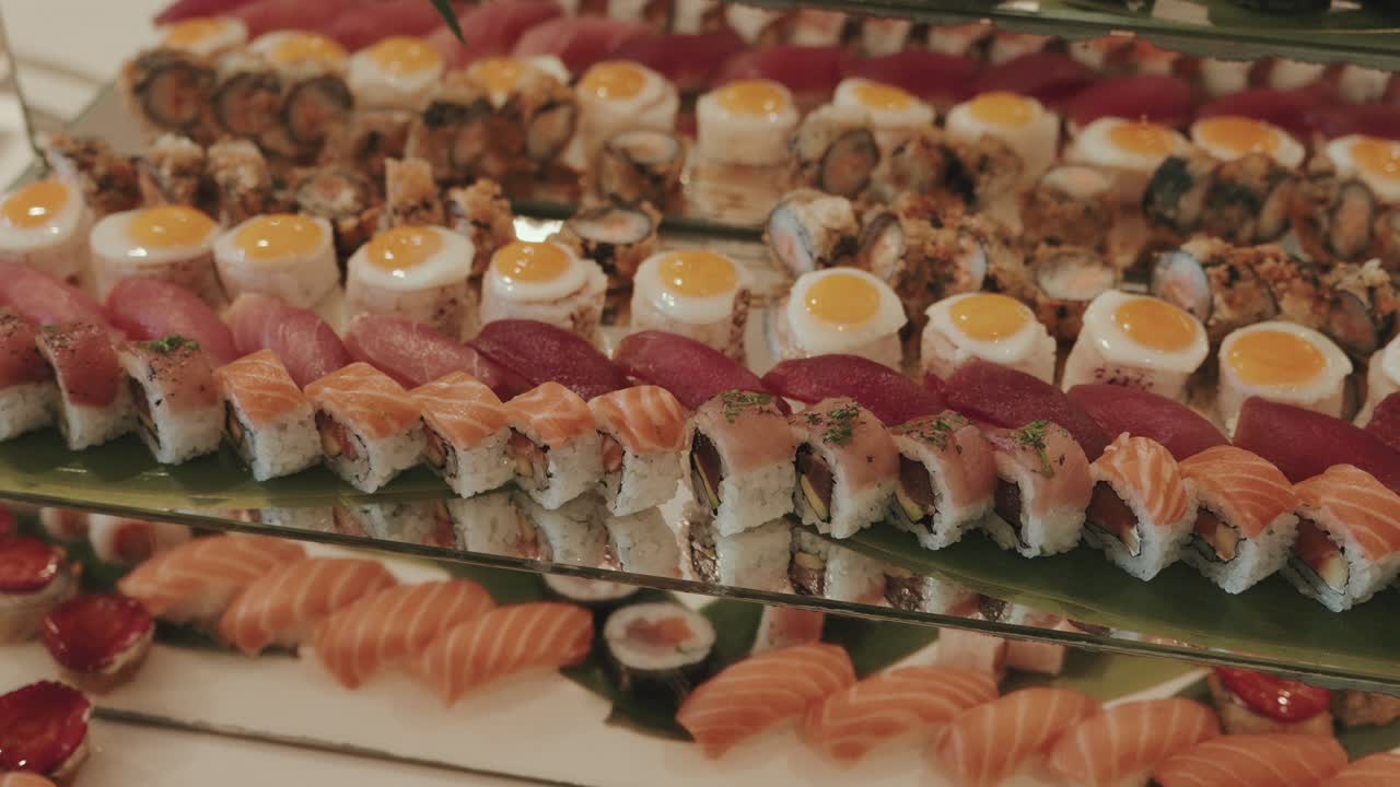 rows of colorful sushi and quail egg appetizers on elegant mirrored platters at buffet
