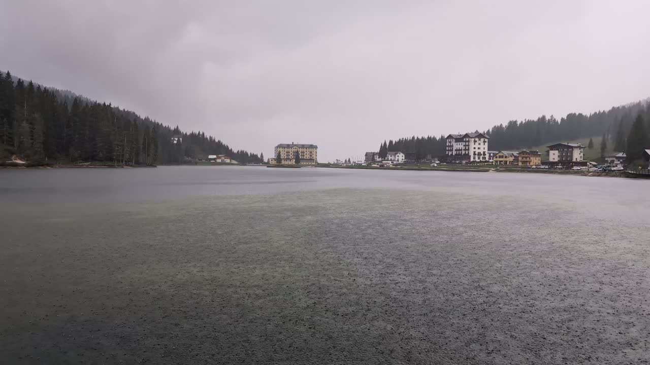 Rain drops on the lake with dark cloudy sky, Misurina lake, Dolomites
