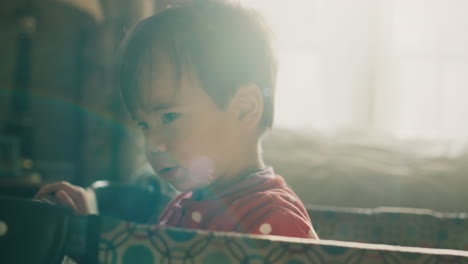 A-portrait-of-a-cute-Asian-baby,-standing-in-his-crib.-The-light-from-the-window-illuminates-it