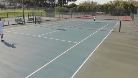 diverse male tennis players holding rackets and playing tennis at court