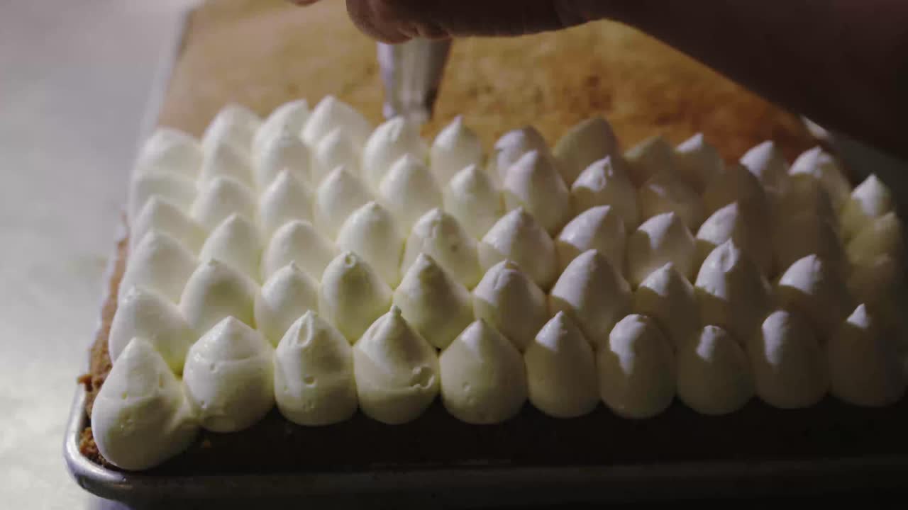 겹겹이 쌓인 케이크에 아이싱이나 프로스팅을 짜는 생과자 요리사