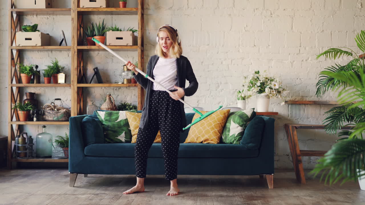 Kvinde danser, mens hun gør rent med moppe