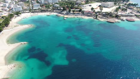 drone view in albania flying over white sand beaches, blue crystal clear water, hotels, sunny day in ksamil