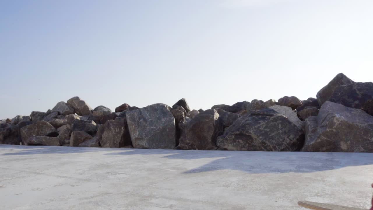 가죽 재 ⁇ 을 입은 멋진 젊은이가 롱보드에 스케이팅하고 있습니다.