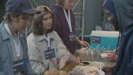 volunteers giving hot meals to homeless people on urban street