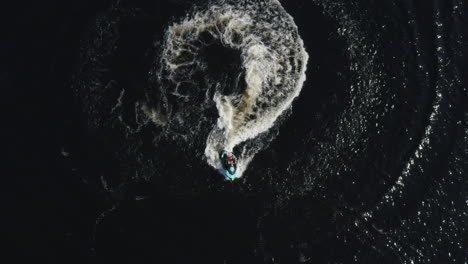 Aerial-top-view-of-a-young-man-riding-a-jet-ski-in-the-sea-in-slow-motion