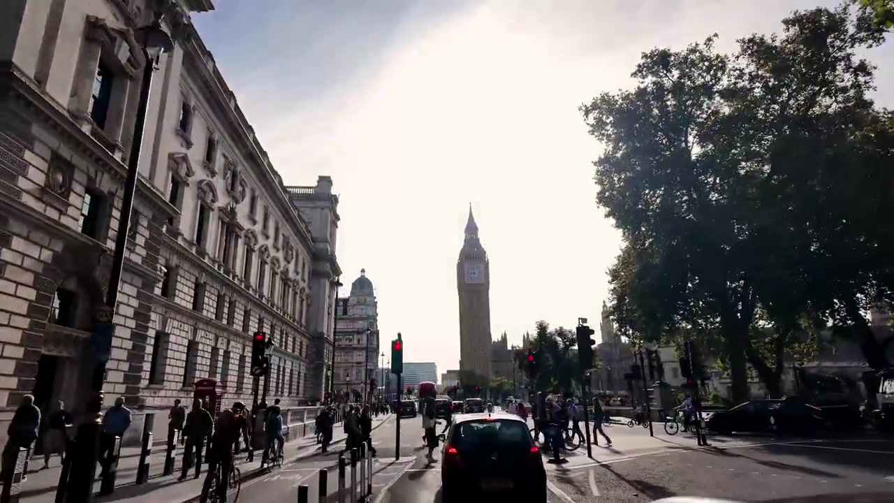 Bagliori del sole tra gli alberi durante un giro in auto per il centro di Londra, con vista sul Big Ben.