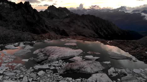 vista aérea de un lago glaciar lleno de icebergs derretidos en partes remotas de los alpes suizos durante la puesta de sol con pan hacia abajo