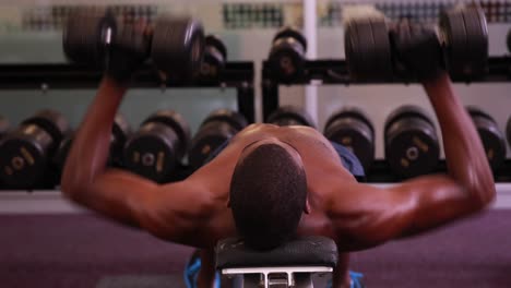 Fit-shirtless-man-lifting-dumbbells-lying-on-bench