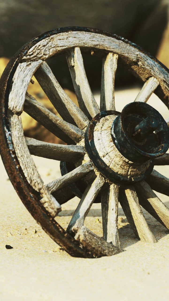 Old wooden wheel on sandy ground in an outdoor setting during daylight
