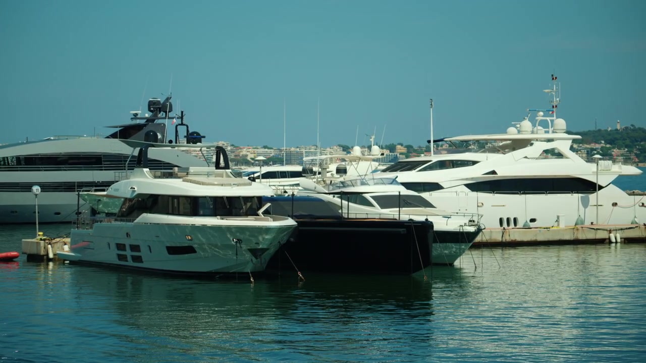 Numerosi yacht di lusso ormeggiati in un porto, che riflettono la luce del sole sull'acqua, rappresentando ricchezza, viaggi e stile di vita.