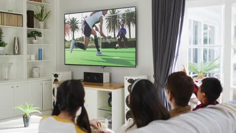 Composite-of-happy-family-sitting-at-home-together-watching-hockey-match-on-tv