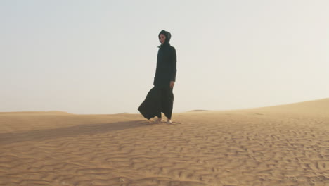 bella mujer descalza con hiyab posando en un desierto ventoso