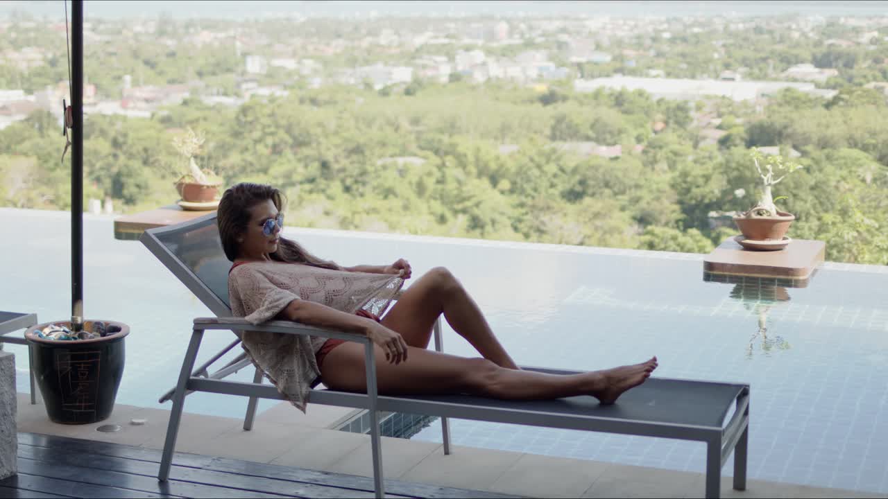 mujer acostada en una silla de sol en la terraza de la piscina del hotel