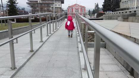 niño corriendo con una chaqueta roja y una bufanda blanca