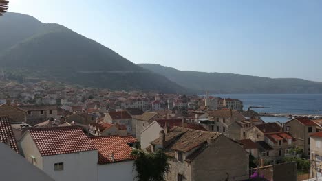 Old-town-by-the-sea-and-mountains,-Komiza,-Vis-Island,-Croatia,-rising-shot