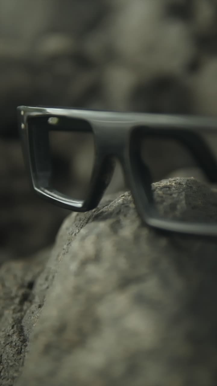 Glasses resting on rocks, soft lighting, nature setting with a calm and serene atmosphere