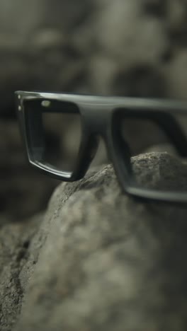 glasses resting on rocks, soft lighting, nature setting with a calm and serene atmosphere