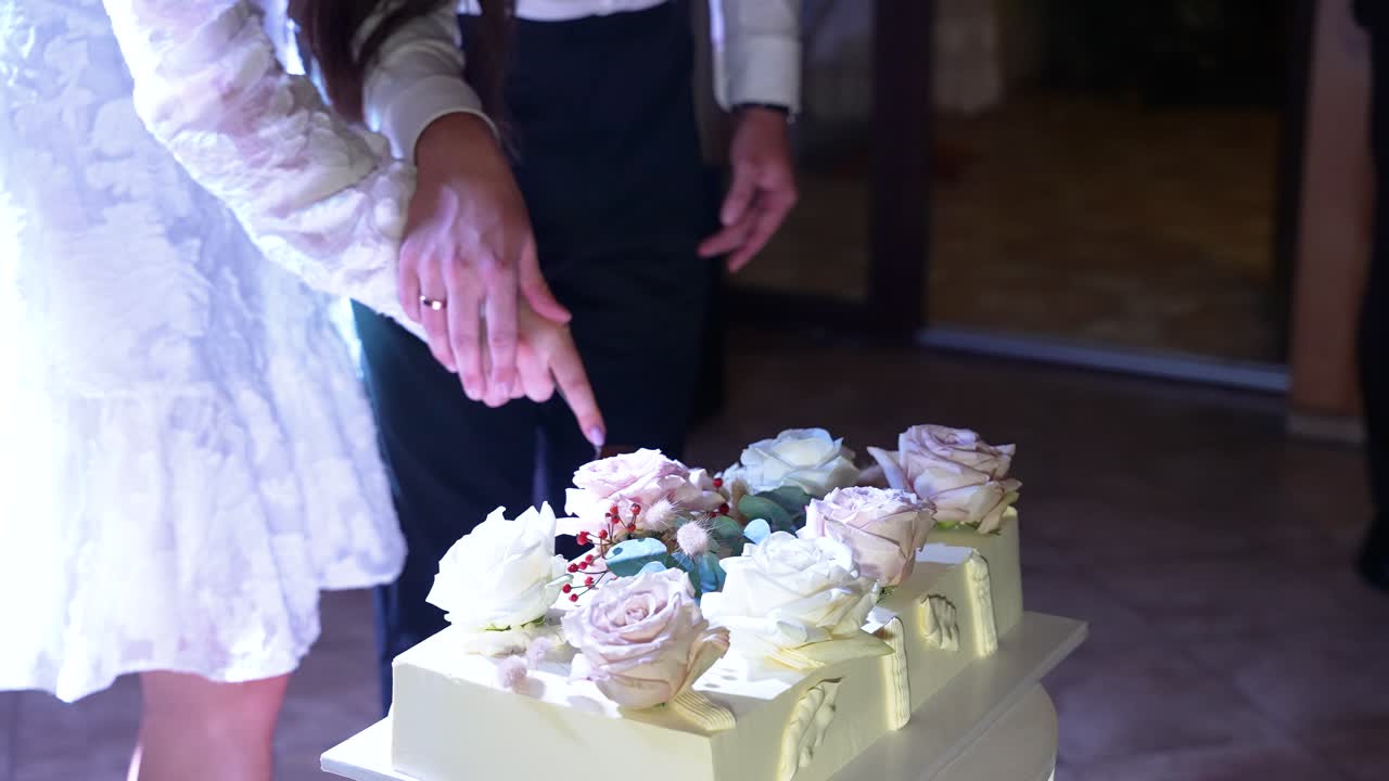 Capture la esencia de la celebración con este íntimo momento de corte de pastel. Una pareja vestida elegantemente comparte una interacción conmovedora bajo una suave iluminación nocturna, creando un recuerdo para atesorar