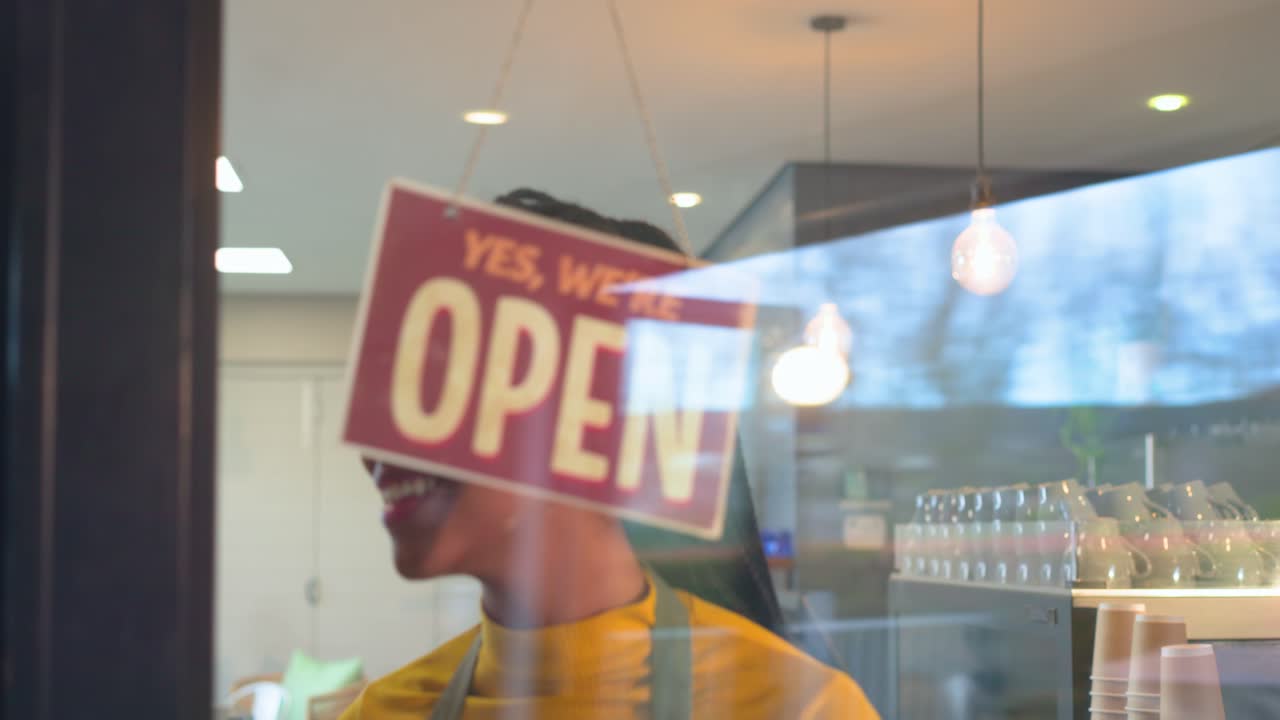 Barista che nota il cartello chiuso sulla porta del bar e lo gira per aprire, accogliendo i clienti
