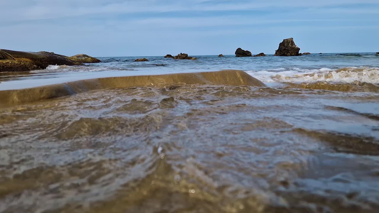 las olas del océano erosionan la playa costera de arena, vista en ángulo bajo