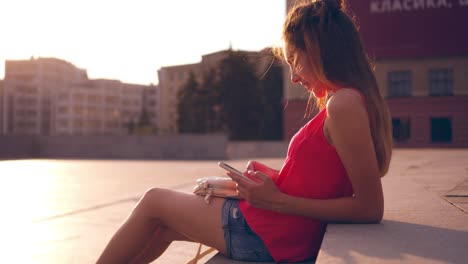 carefree girl texting on phone while sitting on stairs at sunset