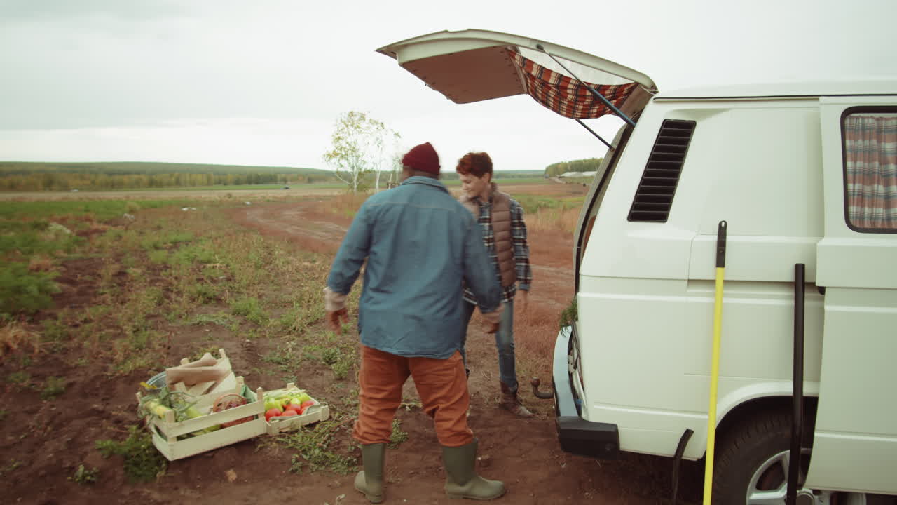 agricultores diversos cargando la cosecha en el tronco de la furgoneta y dando los cinco