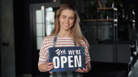 woman holding 'open' sign