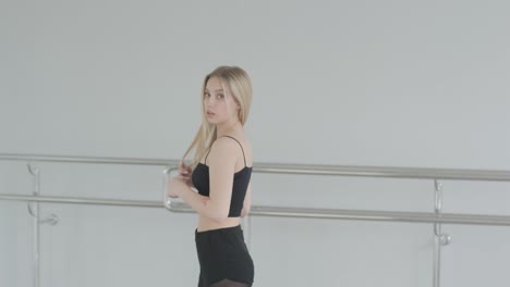 fit girl in black clothes performing contemporary. female dancer shows flowing motions, body and hands waves at white room. modern ballet dance choreography. young woman is moving smoothly