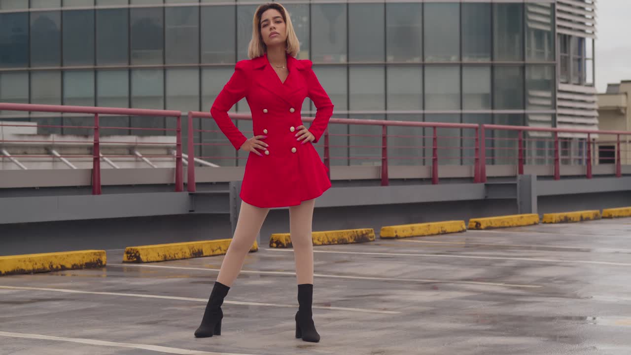 Nello skyline di Port of Spain, Trinidad, una giovane ragazza di origine ispanica sta in piedi su un tetto con un vestito rosso, circondata da alti edifici
