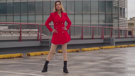 In-the-skyline-of-Port-of-Spain,-Trinidad,-a-young-girl-of-Hispanic-heritage-stands-on-a-rooftop-in-a-red-dress,-tall-buildings-surrounding-her