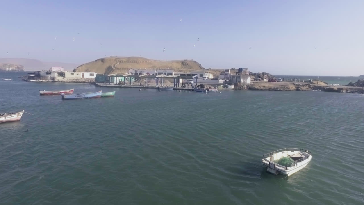 배가 떠다니고 갈매기가 날아다니는 페루 항구에서 바다의 드론으로 축소