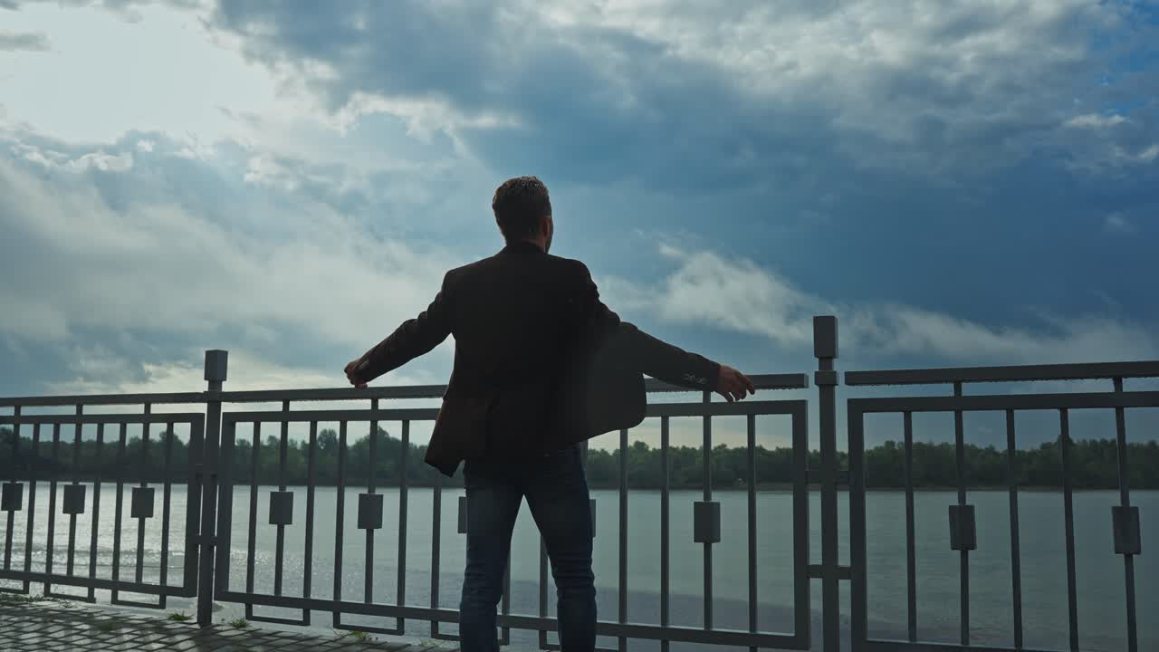 Man standing on a riverbank on a stormy day