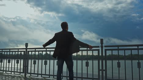 man standing on a riverbank on a stormy day
